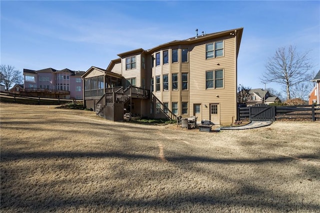 back of house featuring a sunroom, stairway, fence, a gate, and a residential view
