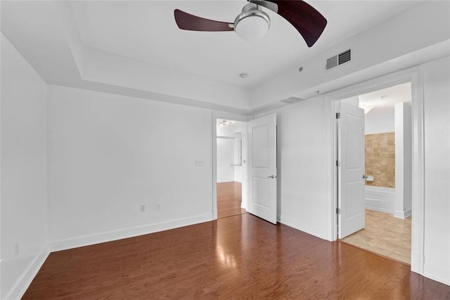 unfurnished bedroom featuring wood-type flooring, ensuite bathroom, and ceiling fan