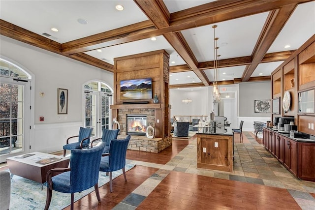 living room featuring beamed ceiling, a stone fireplace, french doors, and coffered ceiling