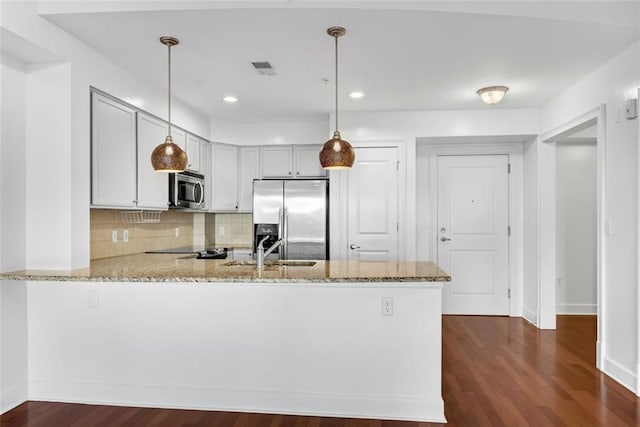 kitchen with hanging light fixtures, tasteful backsplash, light stone counters, kitchen peninsula, and stainless steel appliances