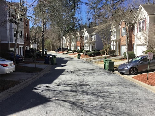 view of road with curbs, a residential view, and traffic signs