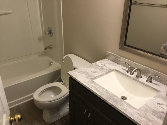 bathroom featuring toilet, wood finished floors, vanity, and shower / tub combination