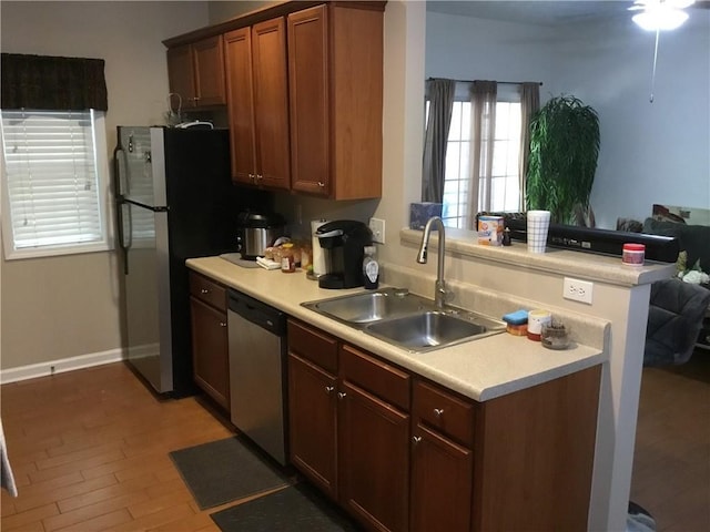 kitchen featuring a peninsula, a sink, light countertops, appliances with stainless steel finishes, and open floor plan