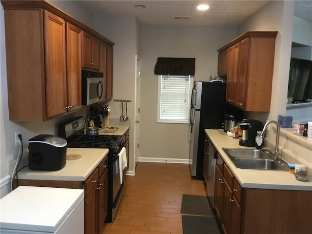 kitchen featuring visible vents, light countertops, appliances with stainless steel finishes, brown cabinetry, and a sink