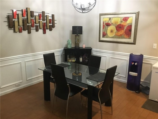 dining area with a chandelier, a wainscoted wall, a decorative wall, and wood finished floors