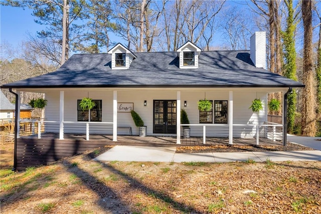 view of front of home featuring french doors, a porch, and a chimney