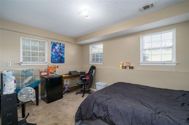 bedroom with a textured ceiling and light colored carpet