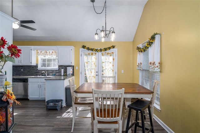 dining area with dark wood-type flooring, lofted ceiling, a wealth of natural light, and ceiling fan with notable chandelier