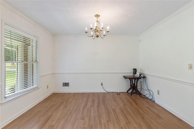 spare room featuring crown molding, light wood-type flooring, and a notable chandelier