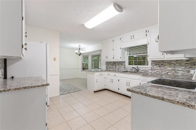 kitchen featuring white cabinets, pendant lighting, a chandelier, and light stone countertops