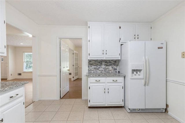 kitchen featuring white cabinets, white fridge with ice dispenser, and light tile patterned floors