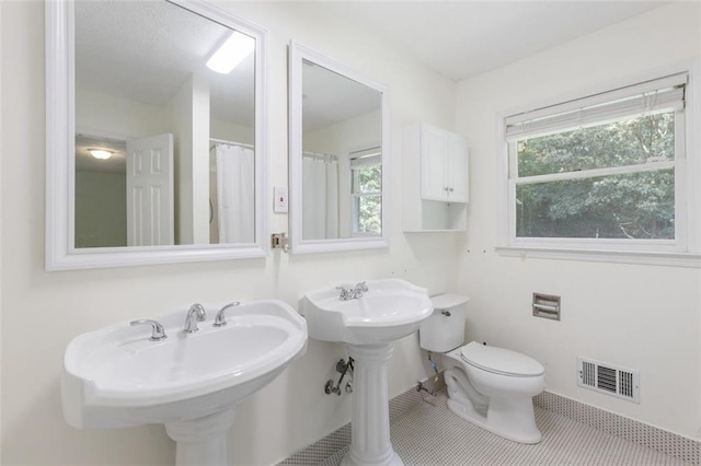 bathroom featuring tile patterned floors, toilet, and a wealth of natural light