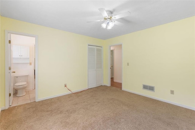 unfurnished bedroom with connected bathroom, ceiling fan, a closet, and light carpet