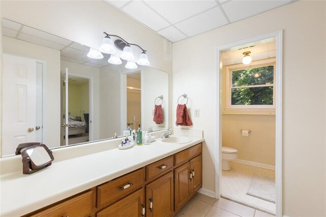 bathroom with tile patterned flooring, vanity, a paneled ceiling, and toilet