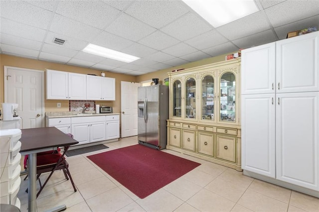 kitchen with a paneled ceiling, white cabinetry, and stainless steel fridge with ice dispenser