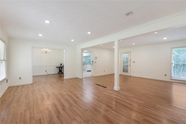 unfurnished living room featuring a chandelier, light hardwood / wood-style flooring, and a healthy amount of sunlight