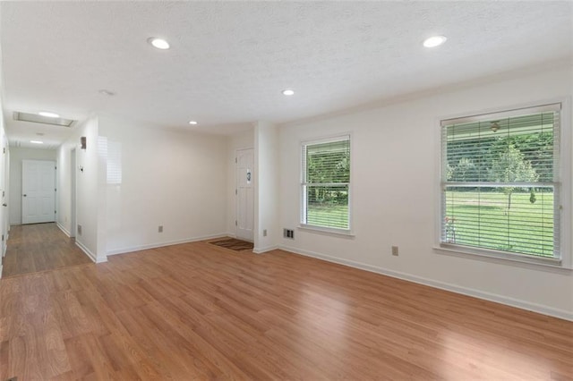 spare room with a textured ceiling and light hardwood / wood-style floors