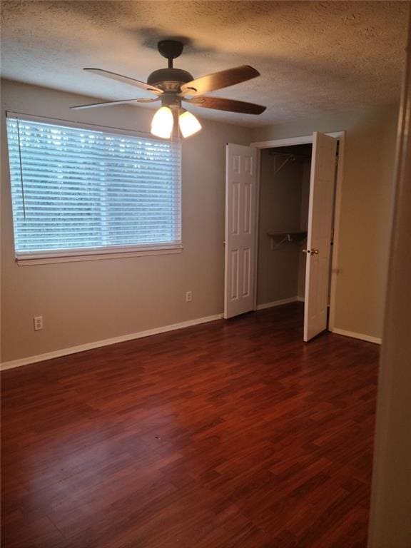 unfurnished bedroom featuring ceiling fan, dark wood-type flooring, a textured ceiling, and a closet