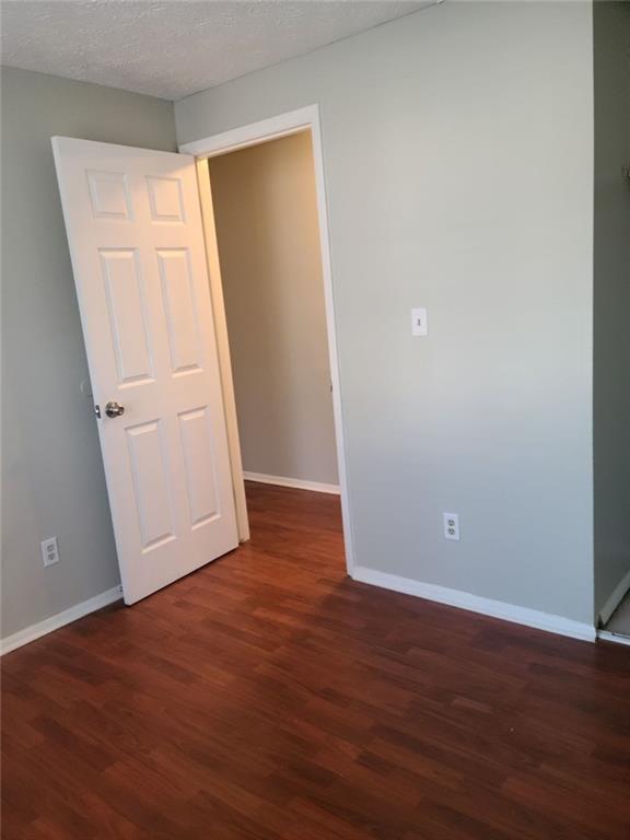 empty room with dark hardwood / wood-style flooring and a textured ceiling