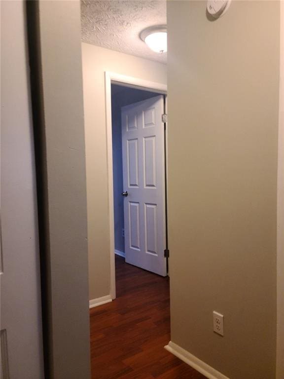 hall with dark hardwood / wood-style floors and a textured ceiling