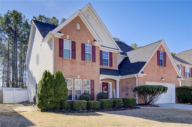 traditional-style house featuring brick siding, concrete driveway, fence, a garage, and a front lawn