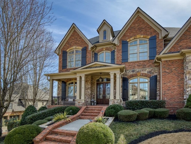 view of front of home with brick siding, french doors, and a porch