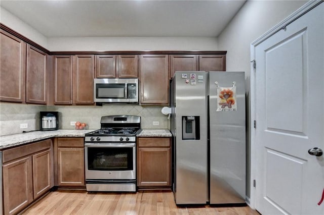 4165 Hammond Bridge Dr, Suwanee, GA 30024 - kitchen featuring stainless steel appliances, light wood-style floors, backsplash, and light stone counters