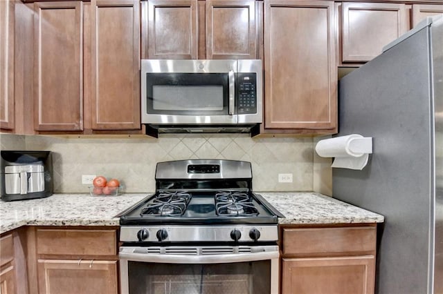 4165 Hammond Bridge Dr, Suwanee, GA 30024 - kitchen featuring appliances with stainless steel finishes, backsplash, and light stone counters