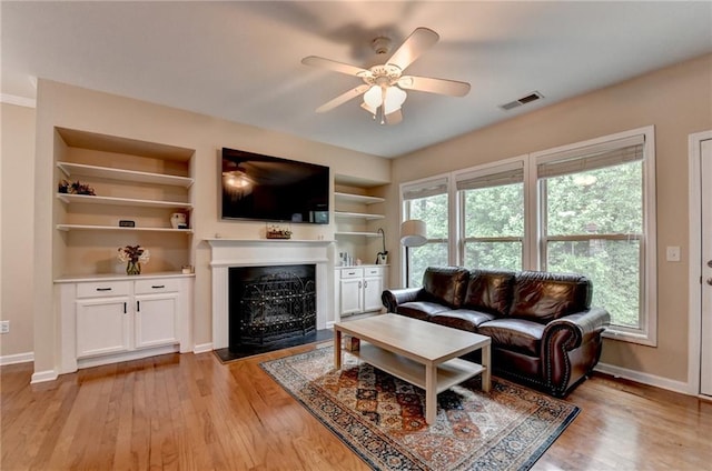 4165 Hammond Bridge Dr, Suwanee, GA 30024 - living area featuring light wood-style flooring, a ceiling fan, a fireplace with flush hearth, and built in shelves