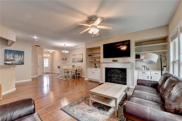 4165 Hammond Bridge Dr, Suwanee, GA 30024 - living area featuring ceiling fan, a fireplace, light wood-type flooring, built in features, and a chandelier