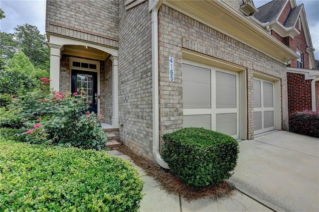 4165 Hammond Bridge Dr, Suwanee, GA 30024 - property entrance featuring concrete driveway, an attached garage, brick siding, and roof with shingles