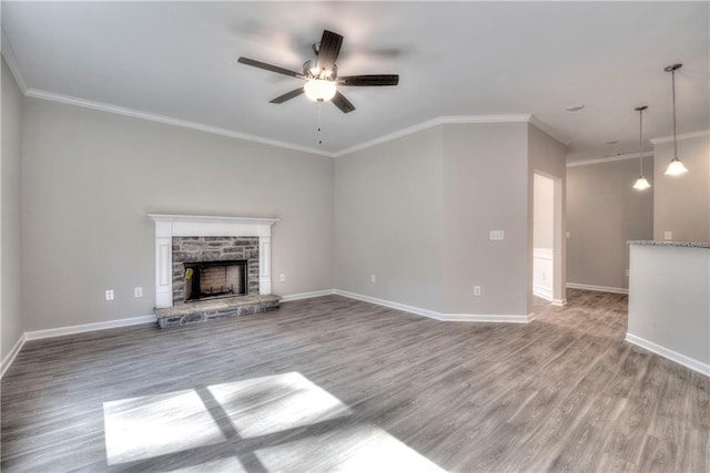 unfurnished living room with hardwood / wood-style floors, a stone fireplace, ceiling fan, and crown molding