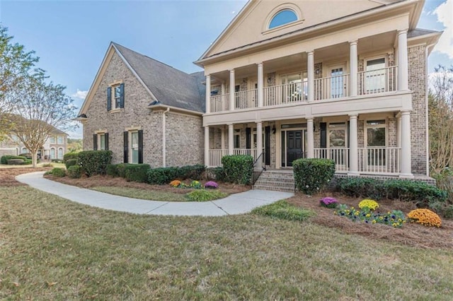 neoclassical / greek revival house with a balcony, a front yard, and a porch