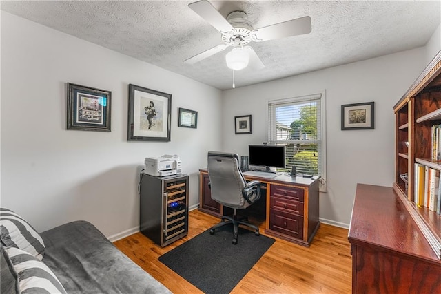 office space featuring ceiling fan, beverage cooler, a textured ceiling, and light wood finished floors