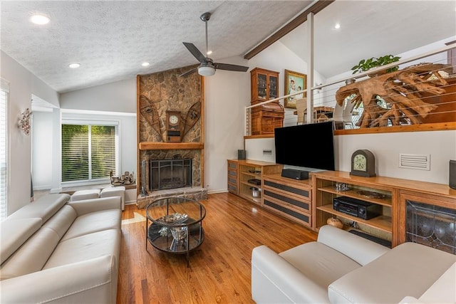 living room with a fireplace, vaulted ceiling, and a textured ceiling