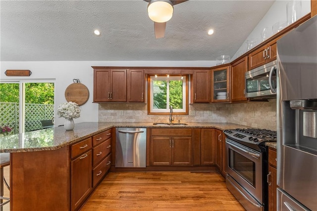 kitchen with stainless steel appliances, a peninsula, a sink, and plenty of natural light
