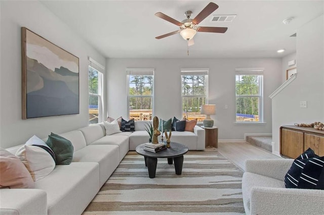 living room featuring light hardwood / wood-style flooring, ceiling fan, and plenty of natural light