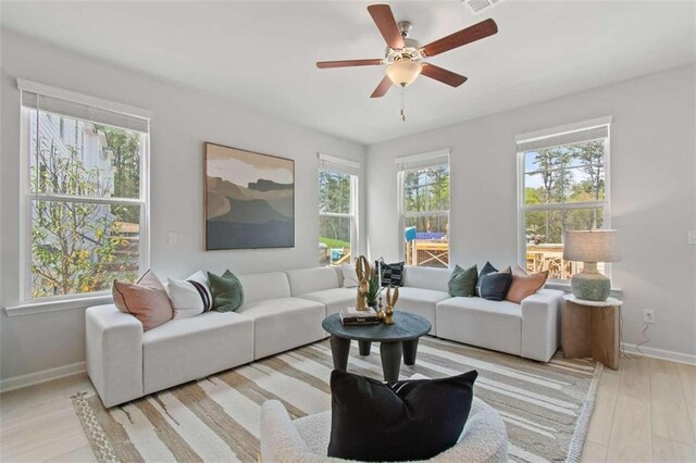 living room with light hardwood / wood-style flooring, ceiling fan, and plenty of natural light