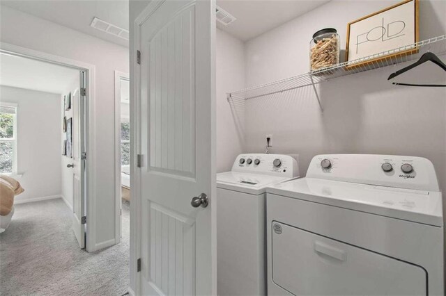 clothes washing area with separate washer and dryer and light colored carpet