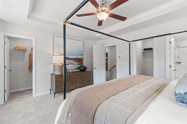 bedroom with a raised ceiling, ceiling fan, and light colored carpet