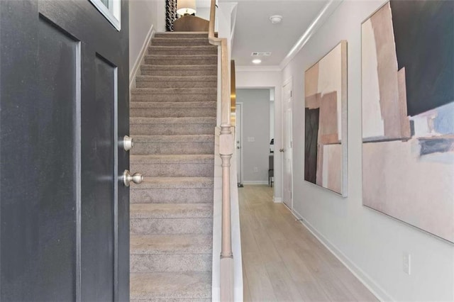 stairs featuring ornamental molding and hardwood / wood-style floors