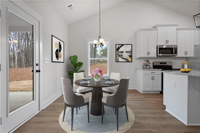 dining room with a notable chandelier, visible vents, baseboards, and wood finished floors