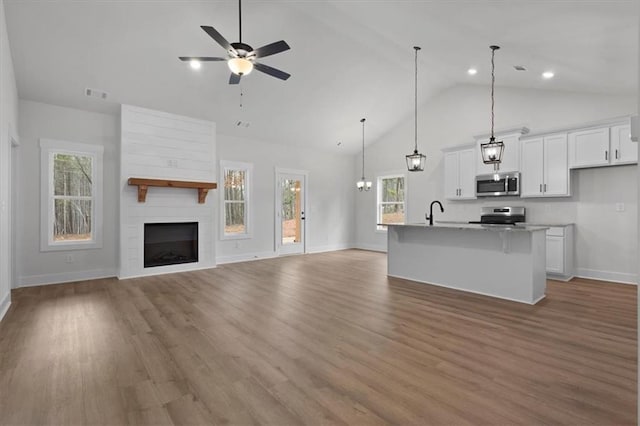 kitchen with a kitchen bar, visible vents, open floor plan, stainless steel appliances, and white cabinets