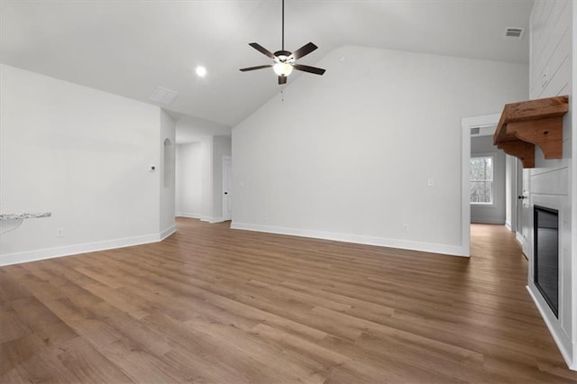 unfurnished living room with visible vents, a large fireplace, baseboards, wood finished floors, and a ceiling fan