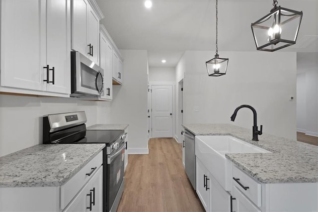 kitchen featuring a center island with sink, white cabinets, appliances with stainless steel finishes, and light wood-style floors