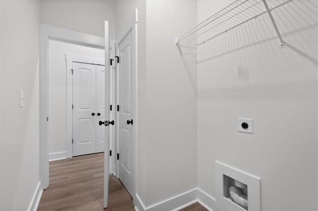 clothes washing area featuring baseboards, hookup for an electric dryer, wood finished floors, and laundry area