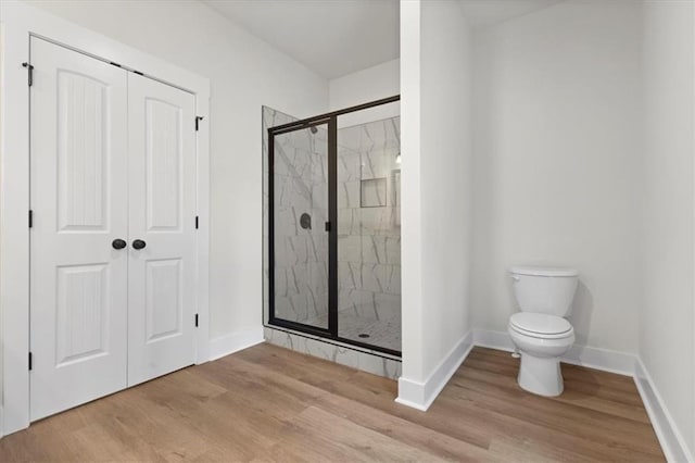 full bathroom with a shower stall, toilet, baseboards, and wood finished floors