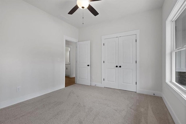 unfurnished bedroom with carpet flooring, baseboards, a closet, and ceiling fan