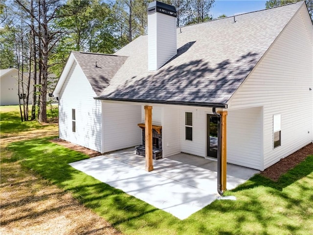 rear view of house featuring a patio area, a chimney, a shingled roof, and a yard