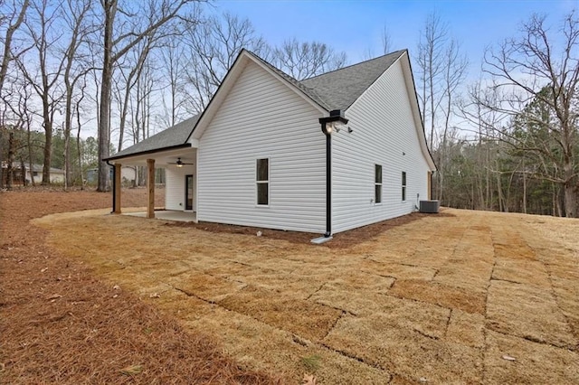 view of home's exterior with central AC unit, a patio, ceiling fan, and roof with shingles